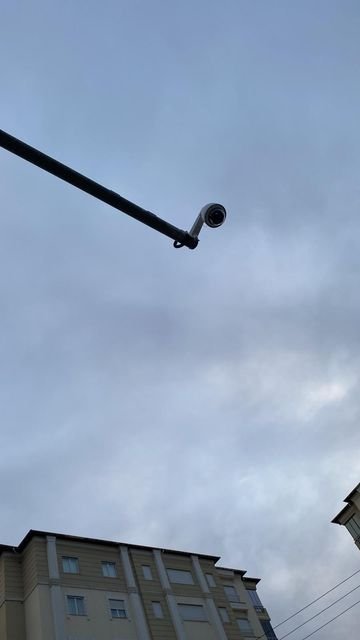 Apartmanlar arasındaki sokağı izleyen direk tipi güvenlik kamerası